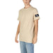 Beige Calvin Klein T-shirt featuring a black logo patch on the sleeve