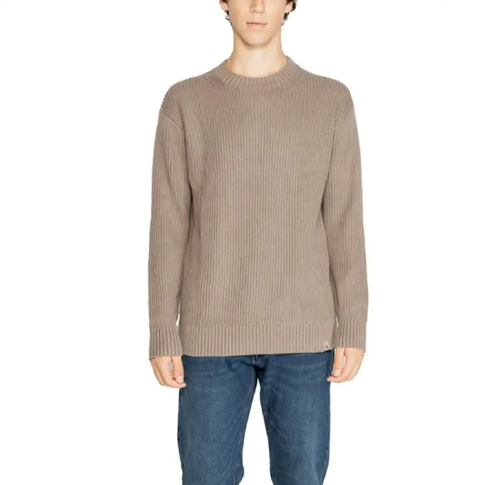 Beige ribbed crewneck sweater styled with blue jeans from Calvin Klein Men’s collection