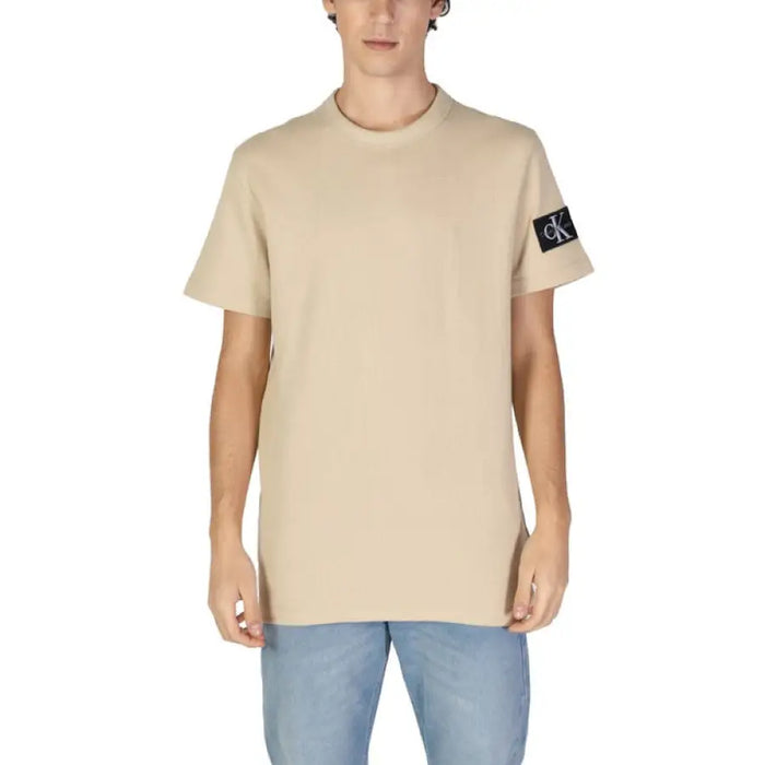 Beige Calvin Klein Men T-Shirt with dark sleeve patch paired with light blue jeans