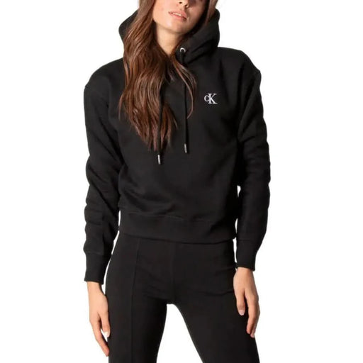 Woman with long brown hair wearing a Black Calvin Klein Jeans hoodie for women