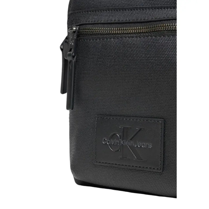 Black Calvin Klein shoulder bag featuring leather logo patch and zipper detail