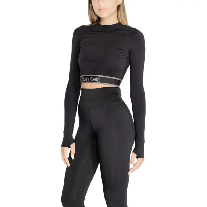 Black Calvin Klein crop top with long sleeves and a branded elastic band at the waist.