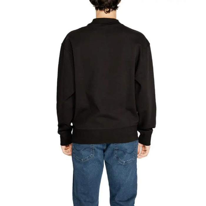 Black crewneck sweatshirt worn by a person, part of Calvin Klein Men Sweatshirts collection