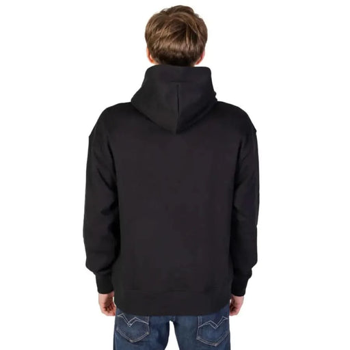 Person wearing black hooded sweatshirt, Tommy Hilfiger Jeans Men Sweatshirts, viewed from behind