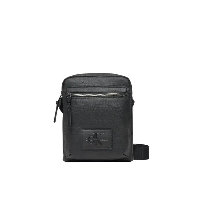 Black leather crossbody bag with zipper compartments and logo patch by Calvin Klein