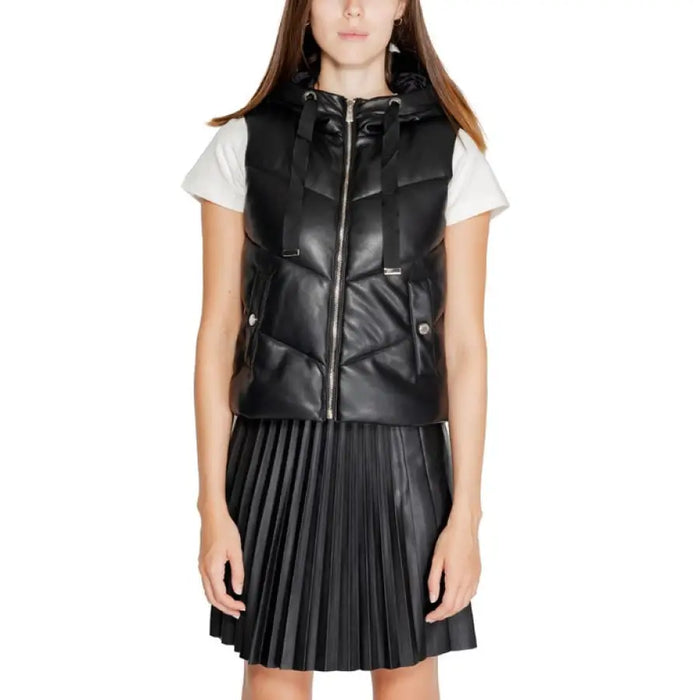 Black leather puffer vest over white t-shirt and pleated black skirt from Morgan De Toi