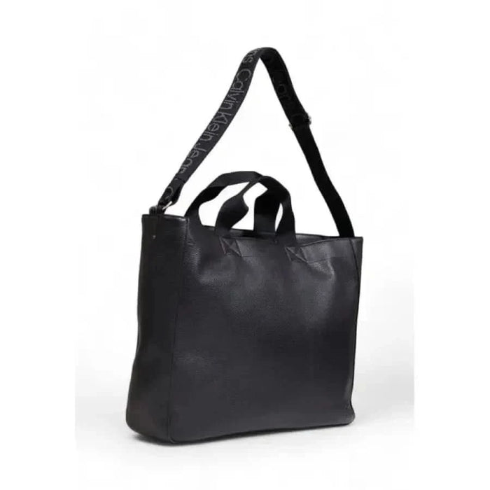 Black leather tote bag with dual handles and a shoulder strap by Calvin Klein