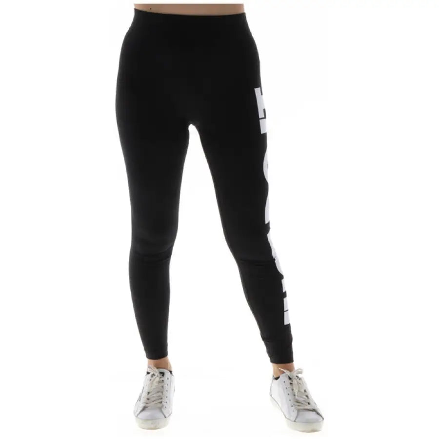 Nike Women’s black leggings with white ’NIKE’ text, paired with white sneakers