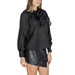 Black long-sleeved blouse with bow neckline paired with leather mini skirt by Jacqueline De Yong