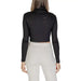 Black long-sleeved cropped turtleneck top paired with white pants from Calvin Klein Jeans