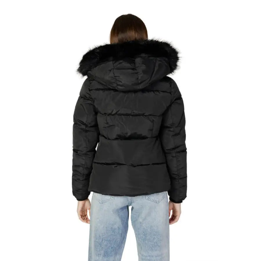 Black puffer jacket with fur-trimmed hood over light blue jeans by Calvin Klein Jeans