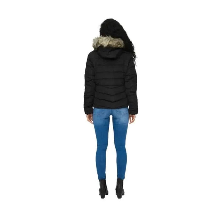 Black puffer jacket with fur-trimmed hood over blue jeans and ankle boots from Only