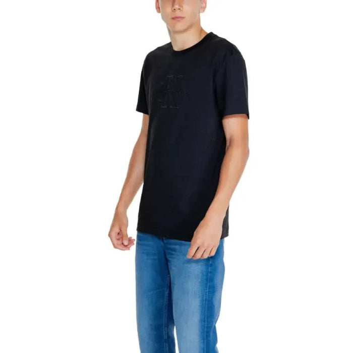 Black short-sleeved Calvin Klein Jeans T-shirt worn by a young man with blue jeans