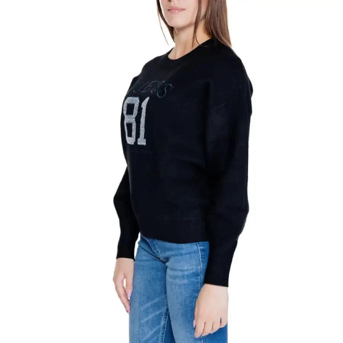 Black sweatshirt ’81’ front with blue jeans from Guess Women Knitwear collection