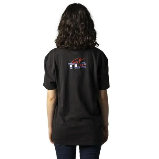 Black t-shirt with ’TLC’ logo on back worn by curly-haired person, Tommy Hilfiger Jeans Women T-Shirt