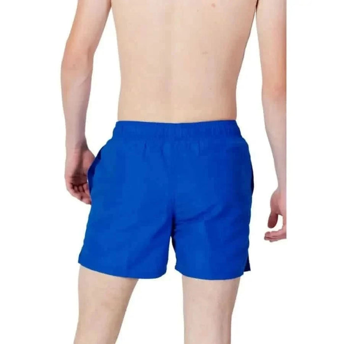 Bright blue swim shorts worn by a person part of Nike Swim Men Swimwear collection