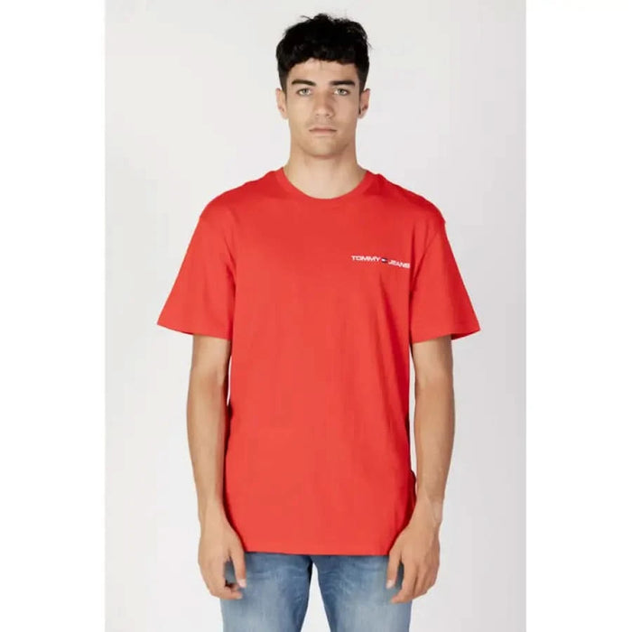 Young man with dark hair wearing a bright red Tommy Jeans T-shirt by Tommy Hilfiger