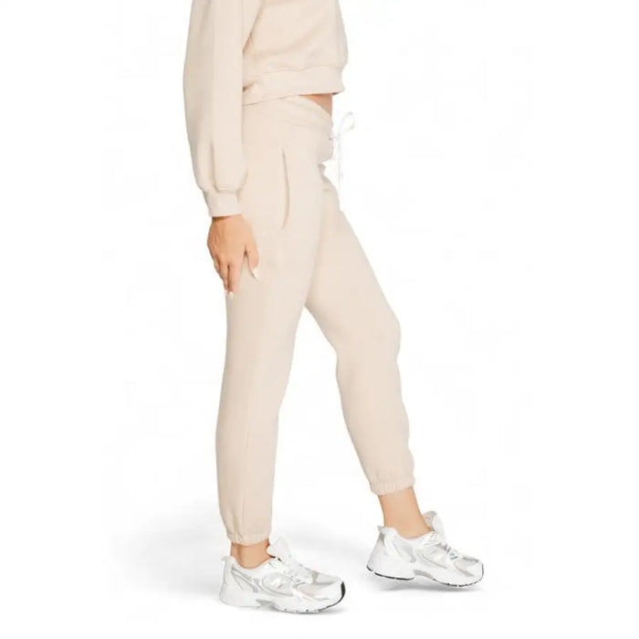 Cream-colored sweatpants with elastic cuffs paired with silver sneakers in Icon Women’s Trousers