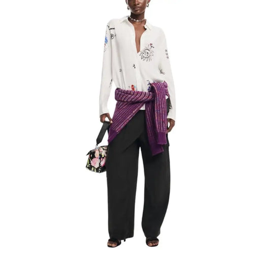 Fashion ensemble with white embroidered blouse, black wide-leg pants, and purple sweater