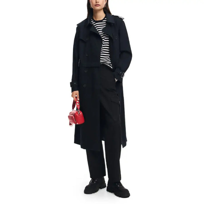 Long black wool coat over striped shirt, black pants, and red handbag by Desigual