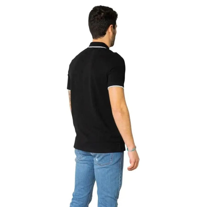 Man in black polo shirt and blue jeans showcasing Armani Exchange Men Polo from behind