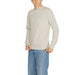 Man in light-colored long-sleeved sweater and blue jeans from Boss Men Knitwear