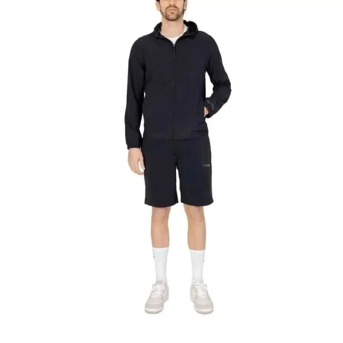 Man wearing Calvin Klein Sport Men Shorts in navy blue with matching jacket, socks, and sneakers