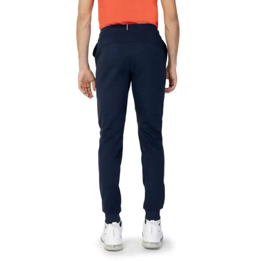 Navy blue slim-fit trousers worn with white sneakers by Le Coq Sportif Men Trousers