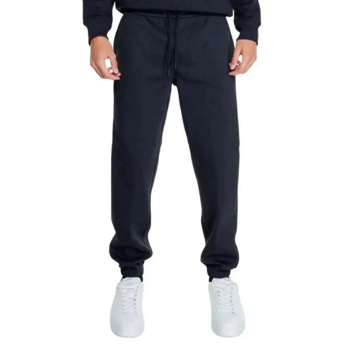 Navy blue Calvin Klein sweatpants with elastic cuffs over white sneakers