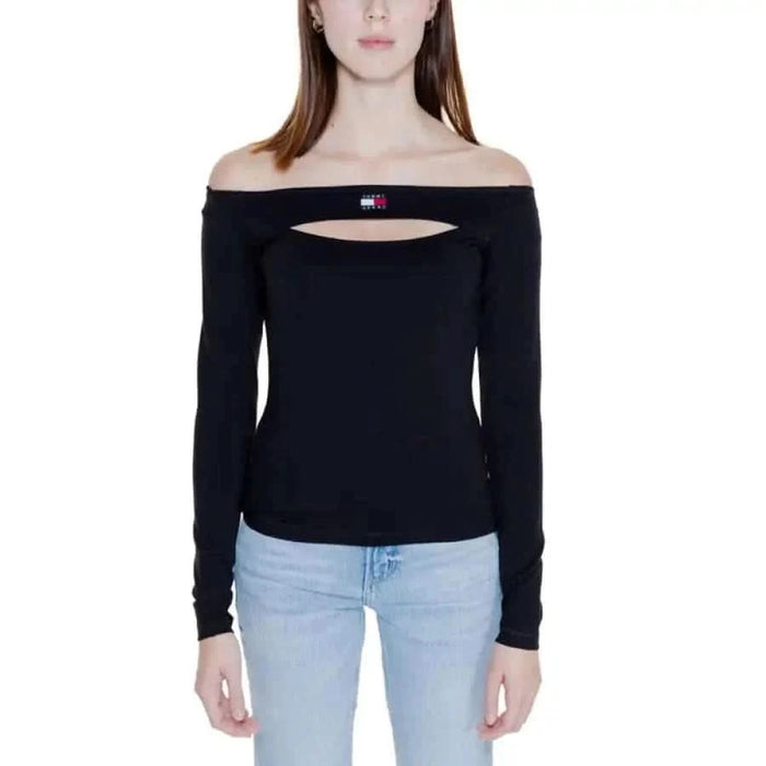 Woman wearing off-shoulder black top with cutout, paired with light blue jeans - Tommy Hilfiger