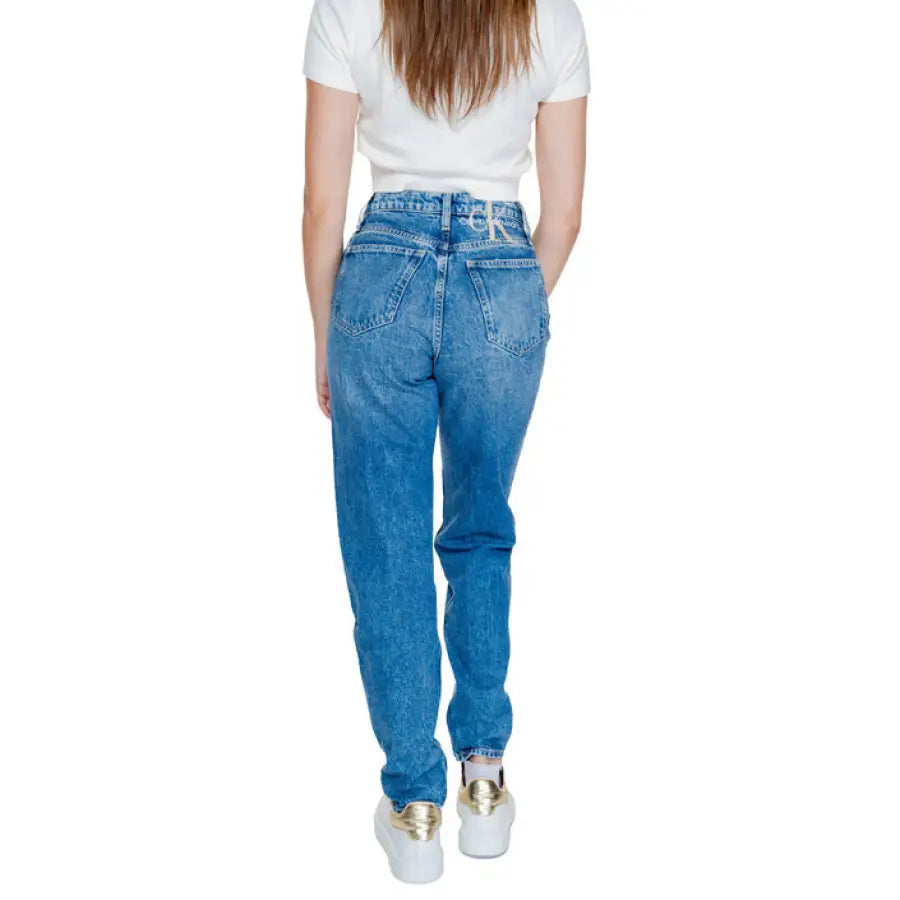 Calvin Klein blue denim jeans with white t-shirt and sneakers. Stylish outfit for women
