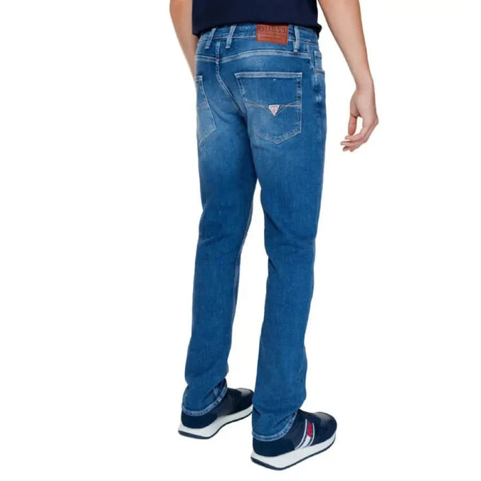 Blue denim jeans by Guess featuring a leather brand patch on the waistband