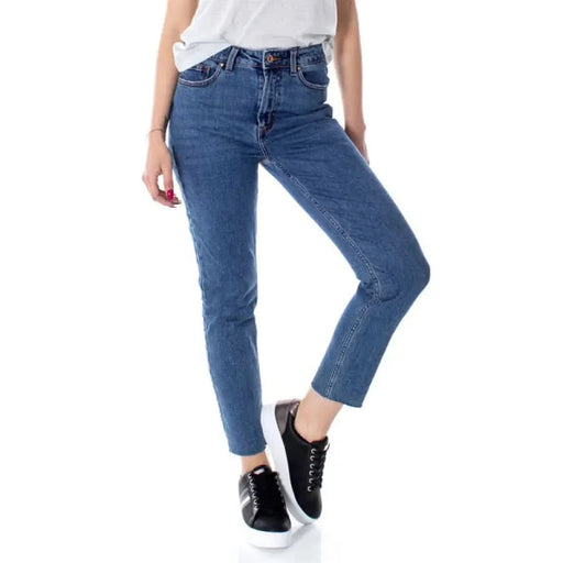 Woman wearing blue denim jeans, white top, and black sneakers from Only Women Jeans collection