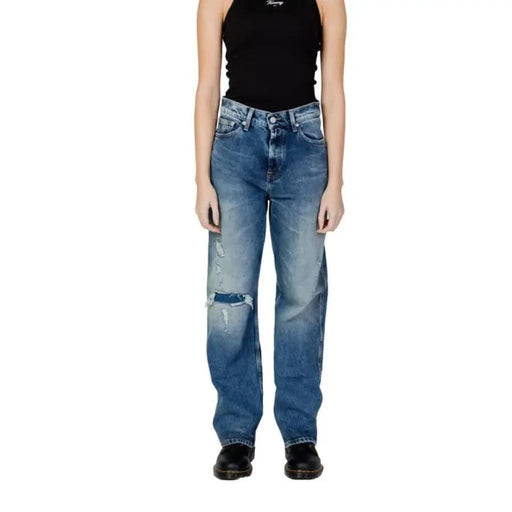 Distressed blue jeans with knee rip, worn with black tank top and shoes. Tommy Hilfiger Jeans