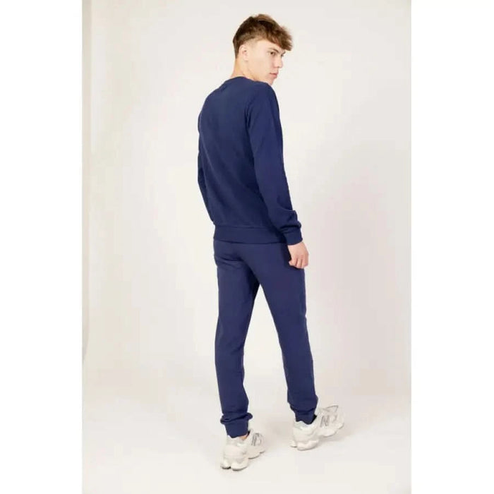 Person in navy blue Fila sweatsuit and white sneakers showcasing Fila Men Knitwear