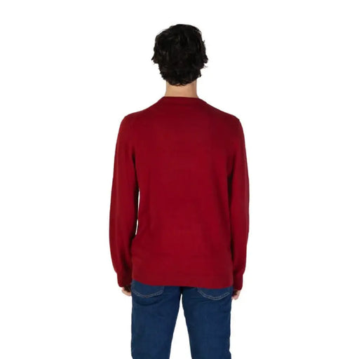 Red knit sweater for men in cotton-cashmere blend worn with blue jeans from behind