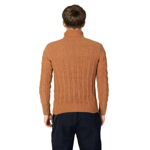 Rust-colored cable knit turtleneck sweater worn by a model from behind, Gianni Lupo