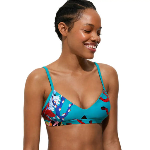 Vibrant teal floral print bikini top showcased by a smiling woman in Desigual beachwear