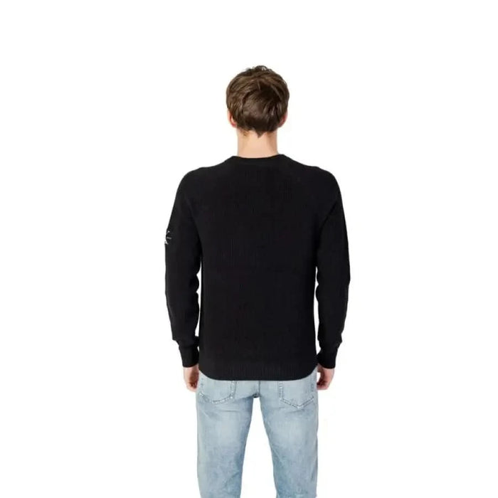 Back view of a person in a black sweater and light blue jeans showcasing Calvin Klein Jeans