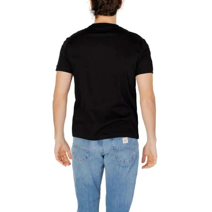 Rear view of a person in a black Ea7 Men T-Shirt and blue jeans