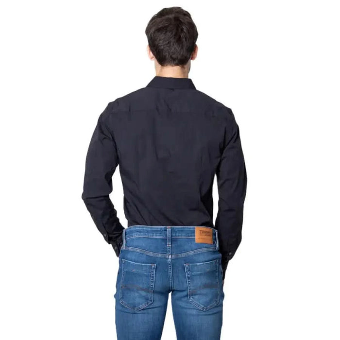 Back view of a person wearing a black dress shirt and blue jeans from Tommy Hilfiger Men Shirt