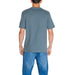 Back view of a person in a gray Calvin Klein Jeans t-shirt and blue jeans ensemble