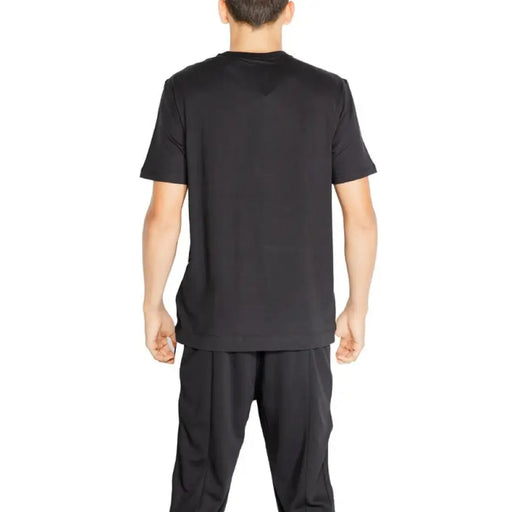 Back view of a person in Calvin Klein Sport black t-shirt and pants outfit