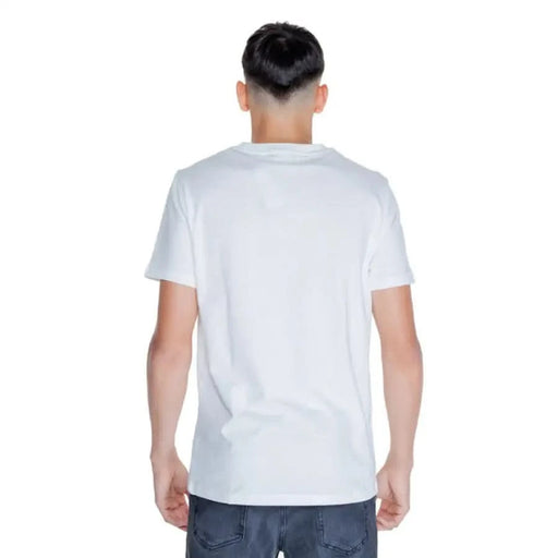 Back view of a person wearing a plain white Peuterey Men T-Shirt and blue jeans