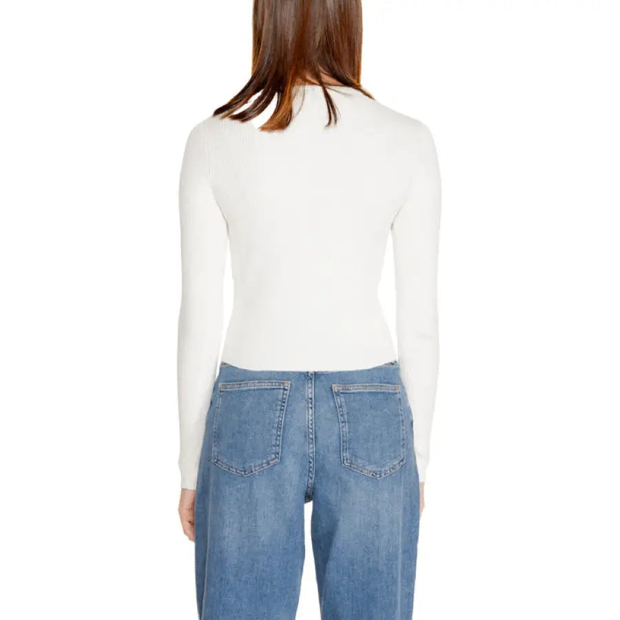 Back view of a woman in a white long-sleeved top and blue jeans from Only Women Knitwear