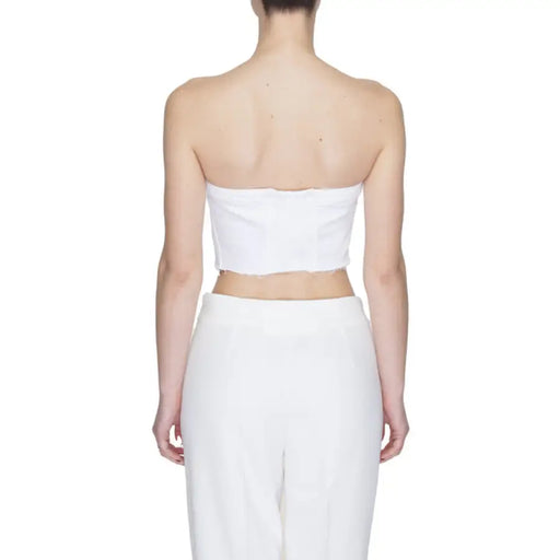 Back view of a person in a white strapless crop top and high-waisted pants by Tommy Hilfiger