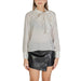 White long-sleeved blouse with bow neckline paired with black faux leather mini skirt