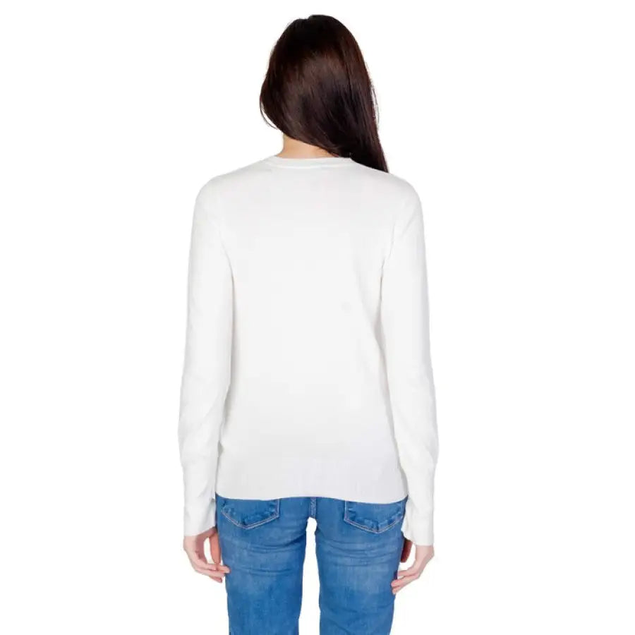 White long-sleeved Guess sweater with blue jeans, seen from behind, part of ’Guess Women Knitwear’