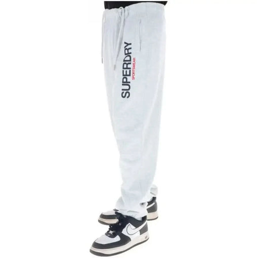 White Superdry sweatpants with vertical logo and black-white sneakers for men