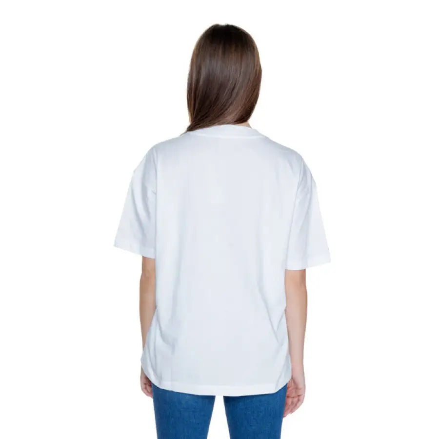 Back view of person with long brown hair wearing a white Calvin Klein Jeans women’s t-shirt